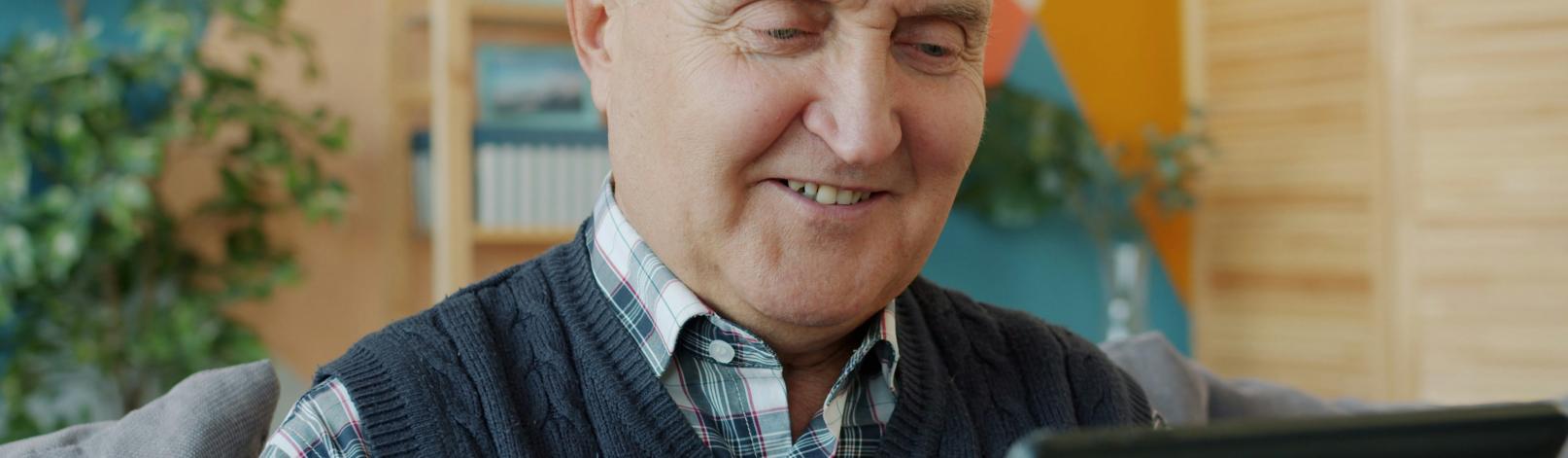 Smilende, eldre mann med iPad