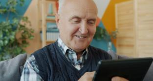 Smilende, eldre mann med iPad