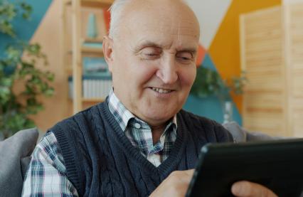 Smilende, eldre mann med iPad